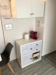 a kitchen with a white dresser and a red appliance at Modernes Zimmer mit Küchenzeile und Bad in Groß Denkte +3 photos