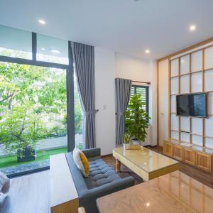 Minh Hung Apartment & Hotel في دا نانغ: غرفة معيشة مع أريكة وتلفزيون