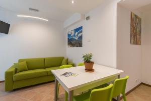 ein Wohnzimmer mit einem Tisch und einem grünen Sofa in der Unterkunft Appartamenti Sarasà in Arco