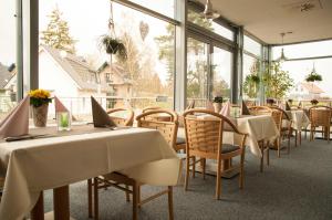 a restaurant with white tables and chairs and windows at Müritz-Strandhotel in Röbel