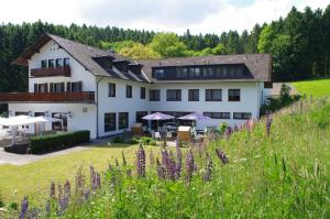 een groot wit gebouw met paarse bloemen ervoor bij Hotel Herrenrest in Georgsmarienhütte