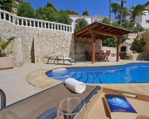 una piscina con pérgola de madera junto a una casa en Villa Castillo - detached villa by Holiday Rentals Villamar, en Benissa