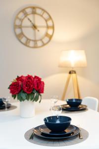 una mesa con dos platos y un reloj en la pared en Le petit Barclay - Appartement privé de 45 m2 - 2 a 4 personnes - Parking gratuit, en Metz