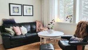 a living room with a black leather couch and a table at Lofoten Home Apartment in Leknes