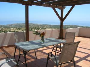 una mesa con sillas y un jarrón de flores en el balcón en Villa Kastri, en Gavdos