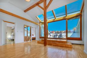 an empty living room with large windows and wooden floors at Downtown Suites Kodanska in Prague