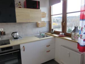 a kitchen with white cabinets and a sink and a window at MyMara , Apartmán Ivadella in Bešeňová