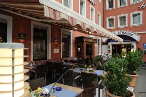 un restaurant avec des tables et des chaises en face d'un bâtiment dans l'établissement City Partner Hotel Strauss, à Wurtzbourg