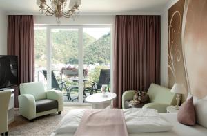 a hotel room with a bed and a balcony at Moselstern Parkhotel Krähennest in Löf