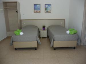 two beds with green pillows in a room at Christothea Apartments in Ayia Napa