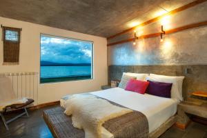 Un dormitorio con una cama grande y una ventana en Hotel Altiplanico Puerto Natales en Puerto Natales