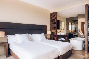 a bedroom with a large bed and a bathroom at Iberostar Selection Lagos Algarve in Lagos