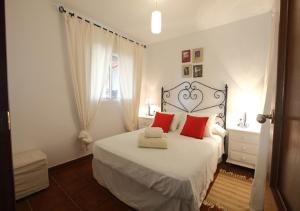 ein Schlafzimmer mit einem großen weißen Bett mit roten Kissen in der Unterkunft LA CASA DE LA PLAYA 1 in Tarifa