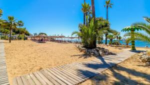 エステポナにあるMarbella Apartment - Beautiful & Spacious next to Marriott Playa Andaluza - PRIVATE HEATED JACUZZIのヤシの木と遊歩道のある砂浜
