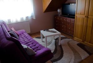 a living room with a purple couch and a table at Bedi Apartmanház in Nagykanizsa