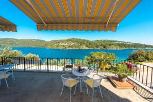 einen Balkon mit einem Tisch und Stühlen sowie Blick auf das Wasser in der Unterkunft Guest House Radulj in Polače