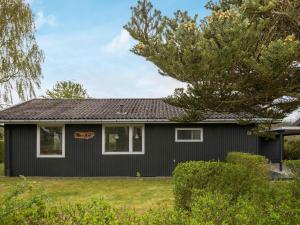 a house with black siding and a tree at Three-Bedroom Holiday home in Juelsminde 15 in Sønderby