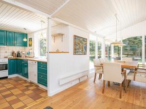 una cocina con armarios verdes y una mesa con sillas en 8 person holiday home in Hj rring en Lønstrup