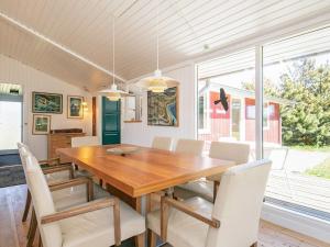 a dining room with a wooden table and white chairs at 8 person holiday home in Hj rring in Lønstrup
