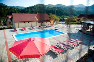 - une vue sur la piscine dotée de chaises et d'un parasol rouge dans l'établissement Motel Flora, à Lepşa