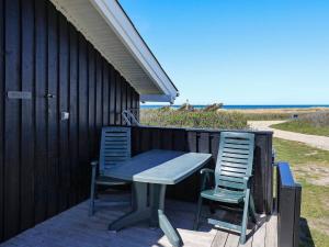 een tafel en twee stoelen op een terras met het strand bij 6 person holiday home in Hj rring in Lønstrup