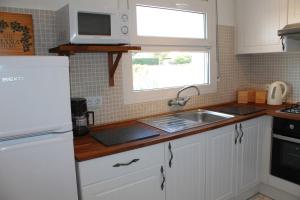 een keuken met witte kasten, een wastafel en een raam bij Alemanya 22 privat pool Estartit in L'Estartit