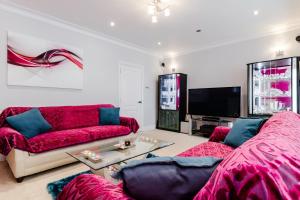 a living room with red couches and a tv at Brooklyn House in Barnet