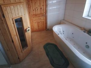 een badkamer met een bad en een groene kruk ernaast bij Ferienhäuser in Allrode in Thale
