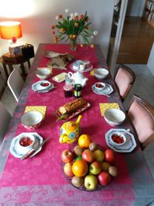 una mesa con un mantel rosa con fruta. en Le Clos Marie en Brénod