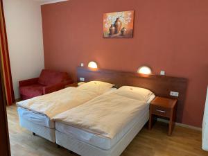 a bedroom with a large bed and a chair at Hotel Restaurant zur Post in Wuppertal