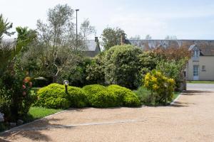 un jardin avec des buissons et des arbres et un bâtiment dans l'établissement Mon Saint Michel, à Ardevon