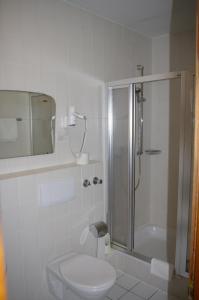 a white bathroom with a shower and a toilet at Hotel Herrenrest in Georgsmarienhütte