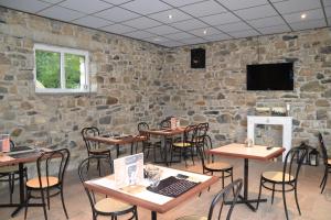 a restaurant with tables and chairs and a stone wall at Gite du Lac in Lourdes