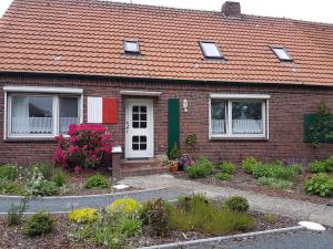 a brick house with a red roof and some flowers at Birkenhof Neuharlingersiel in Neuharlingersiel