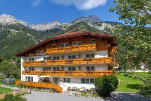 a large building with wooden balconies in front of mountains at Haus Mariandl in Nesselwängle