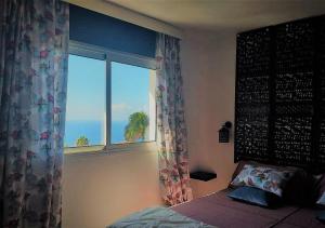 een slaapkamer met een raam met uitzicht op de oceaan bij ZenRepublic, your private villa with outdoor jacuzzi & pool with stunning ocean views in Puntillo del Sol