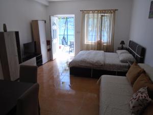a bedroom with two beds and a couch and a television at Apartments Jovanović in Perast