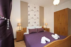 Un dormitorio con una cama morada con zapatos blancos. en Apartments Brnic, en Baška