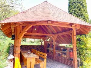 a wooden pavilion with a table and a bench at Pensiunea Eladi in Borşa