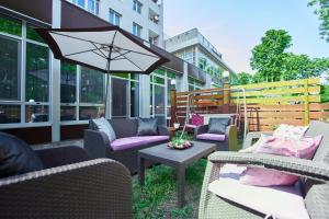 eine Terrasse mit Stühlen, Tischen und einem Sonnenschirm in der Unterkunft Terrace Garden Seaside Apartments in Odessa
