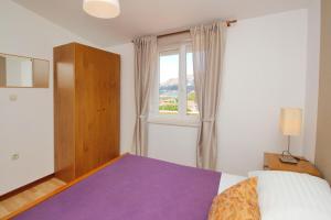 a bedroom with a bed and a window at Apartments Brnic in Baška