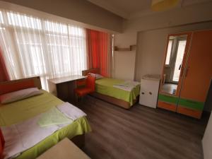 a room with two beds and a desk and a window at Çanakkale Kampüs Pansiyon in Canakkale