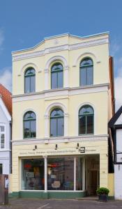 un grand bâtiment jaune avec une façade de magasin dans l'établissement Wohnen am Schlossplatz Oldenburg, à Oldenbourg