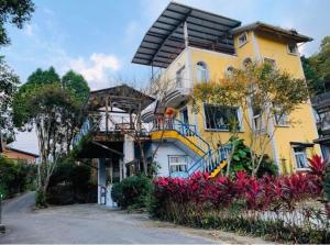 uma grande casa amarela com uma varanda e flores em 築夢咖啡民宿 em Hsinchu