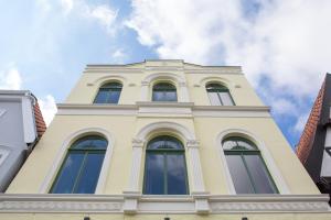 un edificio alto de color amarillo con ventanas en la parte superior en Wohnen am Schlossplatz Oldenburg, en Oldenburg