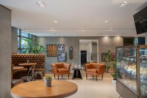 a restaurant with tables and chairs and a lobby at Intercity Curitiba Centro Cívico in Curitiba