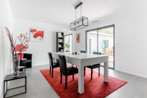a dining room with a white table and black chairs at Villa Géna in Saint-Médard-dʼEyrans