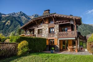 uma grande casa de madeira com montanhas ao fundo em Résidence Chalets Des Bois em Chamonix-Mont-Blanc