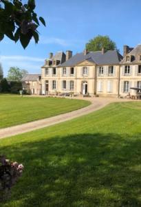 a large house with a large lawn in front of it at Les Escuries in Commes