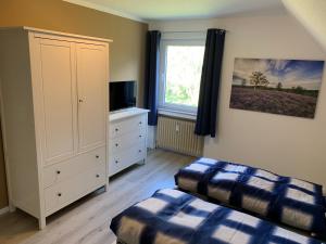 a bedroom with two beds and a dresser and a window at Heidewohnung in Soltau
